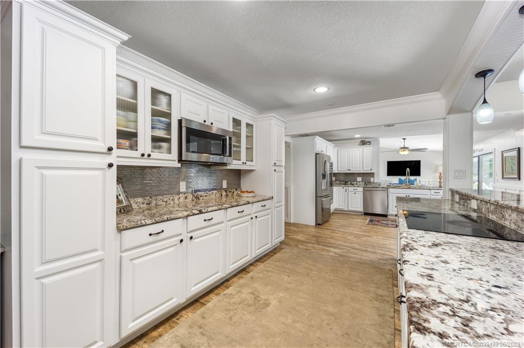 4 Ridgeview Road North Stuart, FL 34996 - Photo 19 of 57 a large kitchen with stainless steel appliances granite countertop a stove top oven a sink dishwasher a dining table and chairs with wooden floor