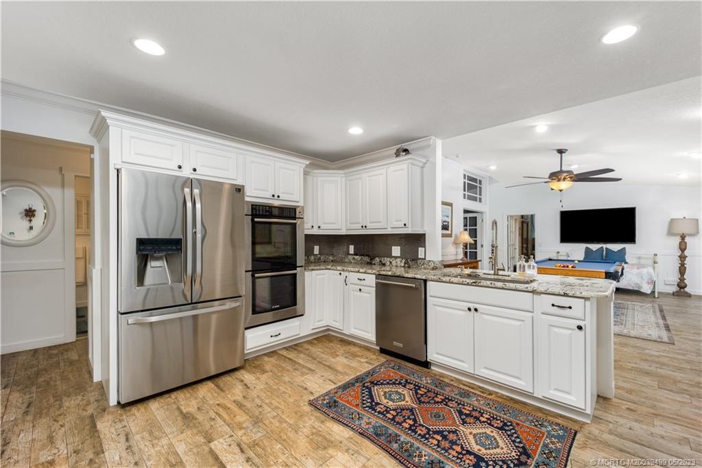 4 Ridgeview Road North Stuart, FL 34996 - Photo 22 of 57 a kitchen with stainless steel appliances granite countertop a refrigerator oven a sink dishwasher and white cabinets with wooden floor