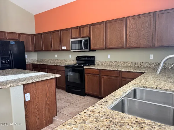 a kitchen with stainless steel appliances kitchen island granite countertop a sink stove and refrigerator