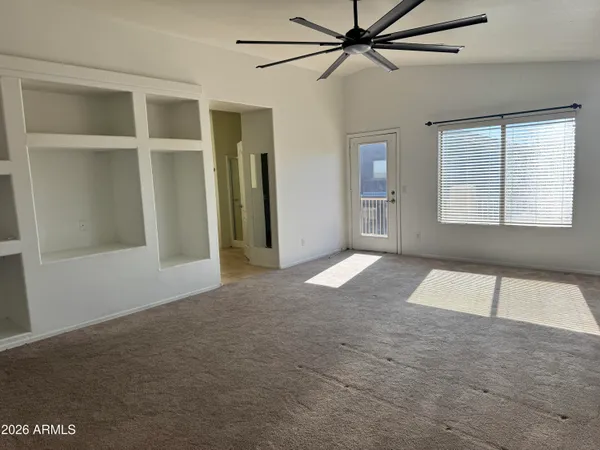 a view of an empty room with a window and a ceiling fan