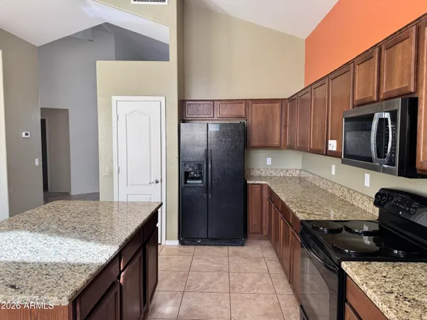 a kitchen with granite countertop kitchen island stainless steel appliances and wooden cabinets