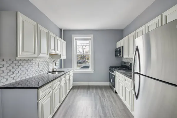 a kitchen with granite countertop a sink stove and refrigerator