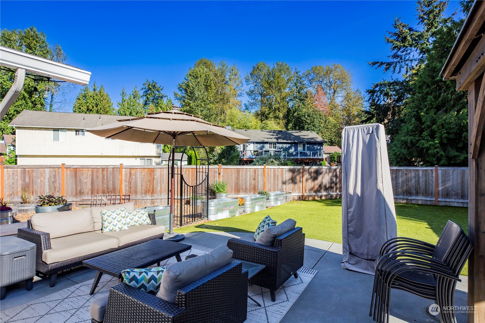 1826 225th Street Southeast Bothell, WA 98021 - Photo 30 of 33 a view of a patio with couches table and chairs under an umbrella with a small yard
