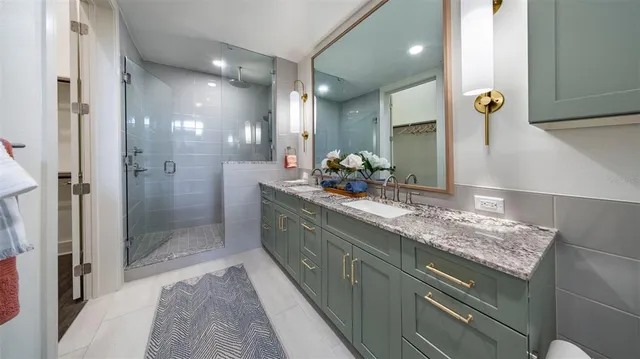 a bathroom with a granite countertop sink two mirror and shower
