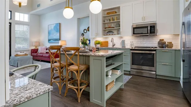 a kitchen with stainless steel appliances granite countertop a stove top oven a sink a dining table and chairs with wooden floor