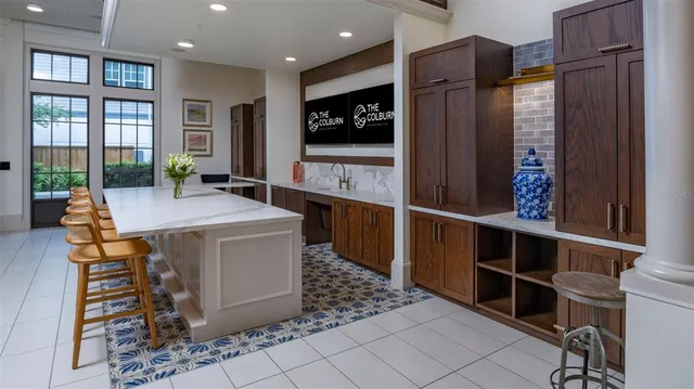 a large living room with stainless steel appliances kitchen island granite countertop a refrigerator a stove and a sink with wooden floor