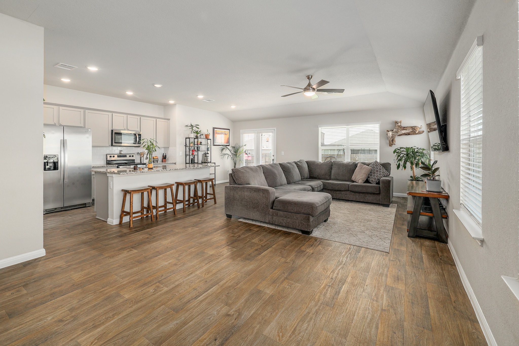 413 Hunter Loop Bertram, TX 78605 - Photo 7 of 27 Inviting open-concept living area with resilient vinyl plank flooring, high ceilings, abundant natural light, and a seamless flow into the kitchen and dining spaces.