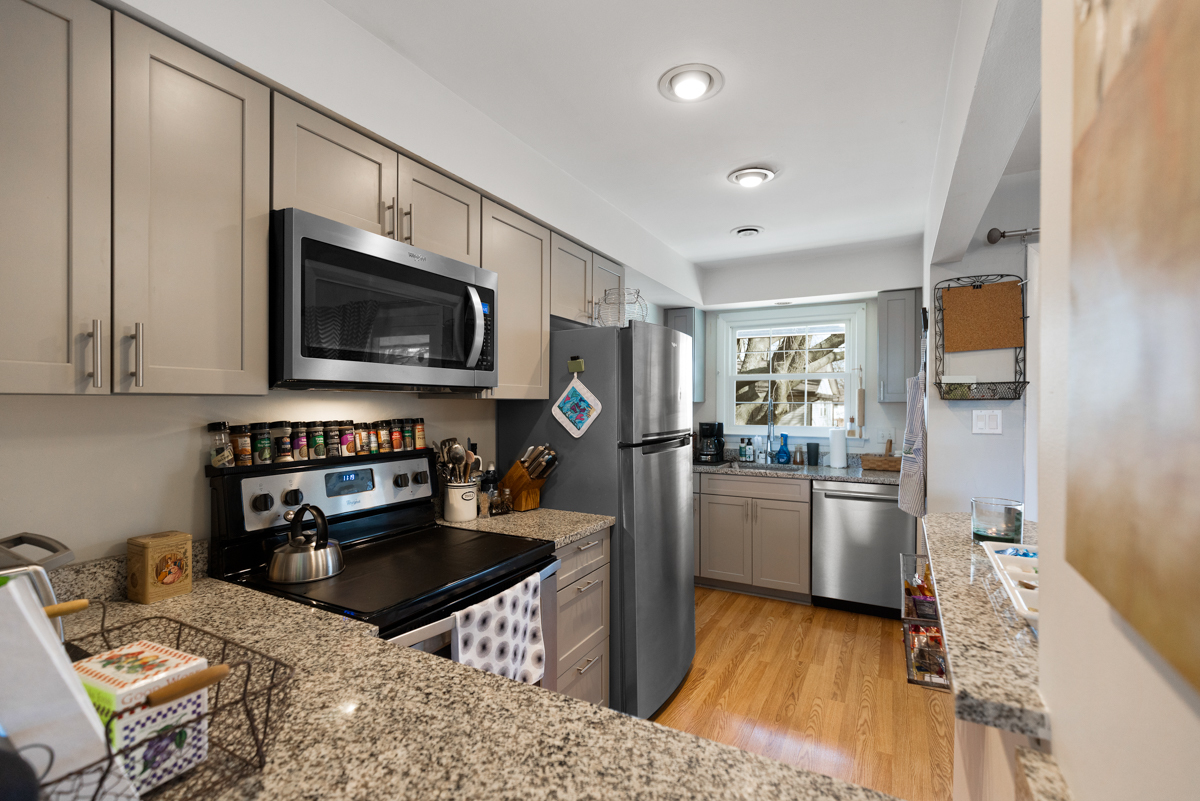 217 Washington Square, Unit D Elk Grove Village, IL 60007 - Photo 5 of 14 a kitchen with stainless steel appliances granite countertop a stove top oven a sink dishwasher a dining table and chairs with wooden floor