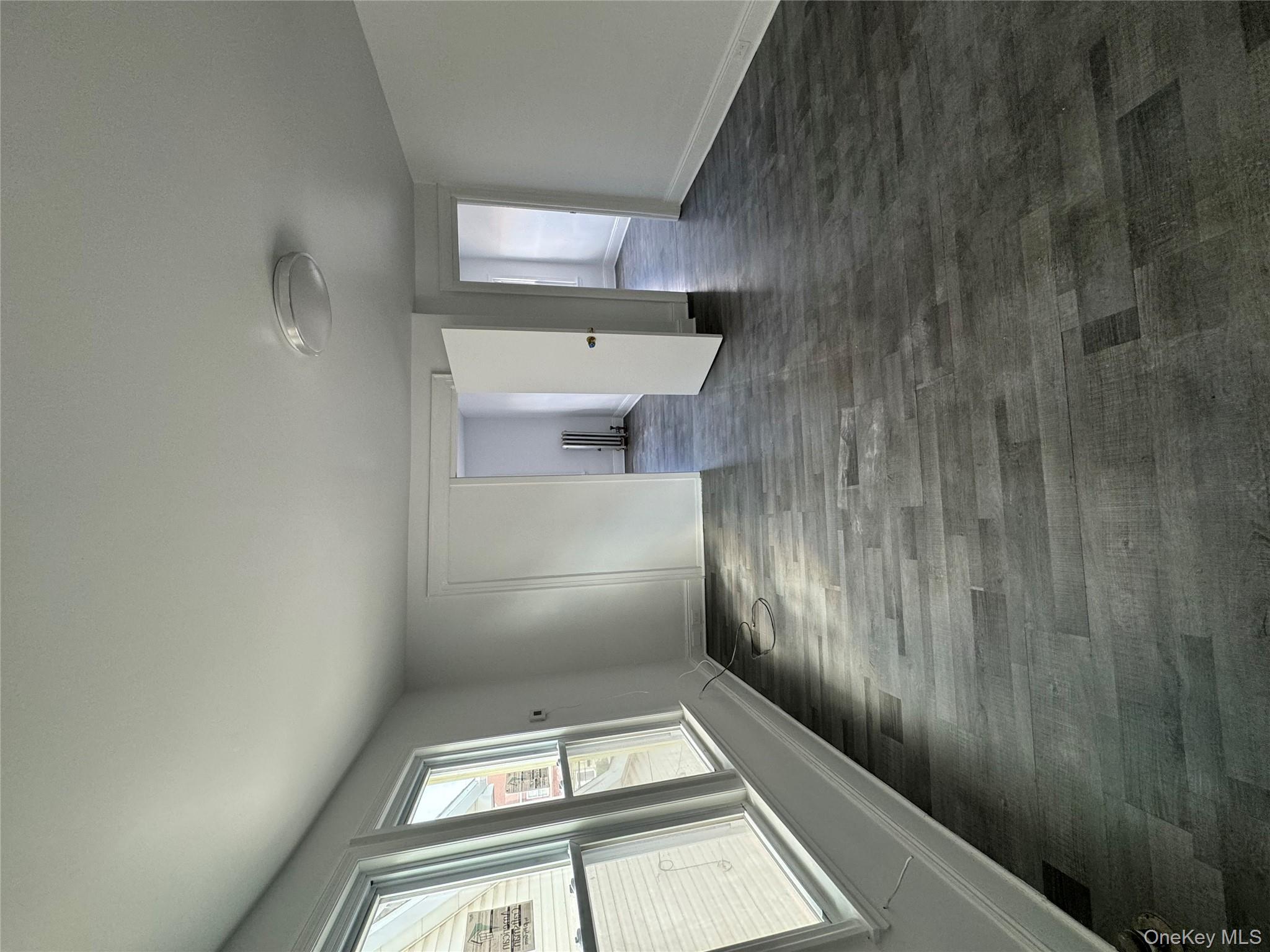 54-13 152nd Street Queens, NY 11355 - Photo 5 of 19 an empty room with wooden floor and windows