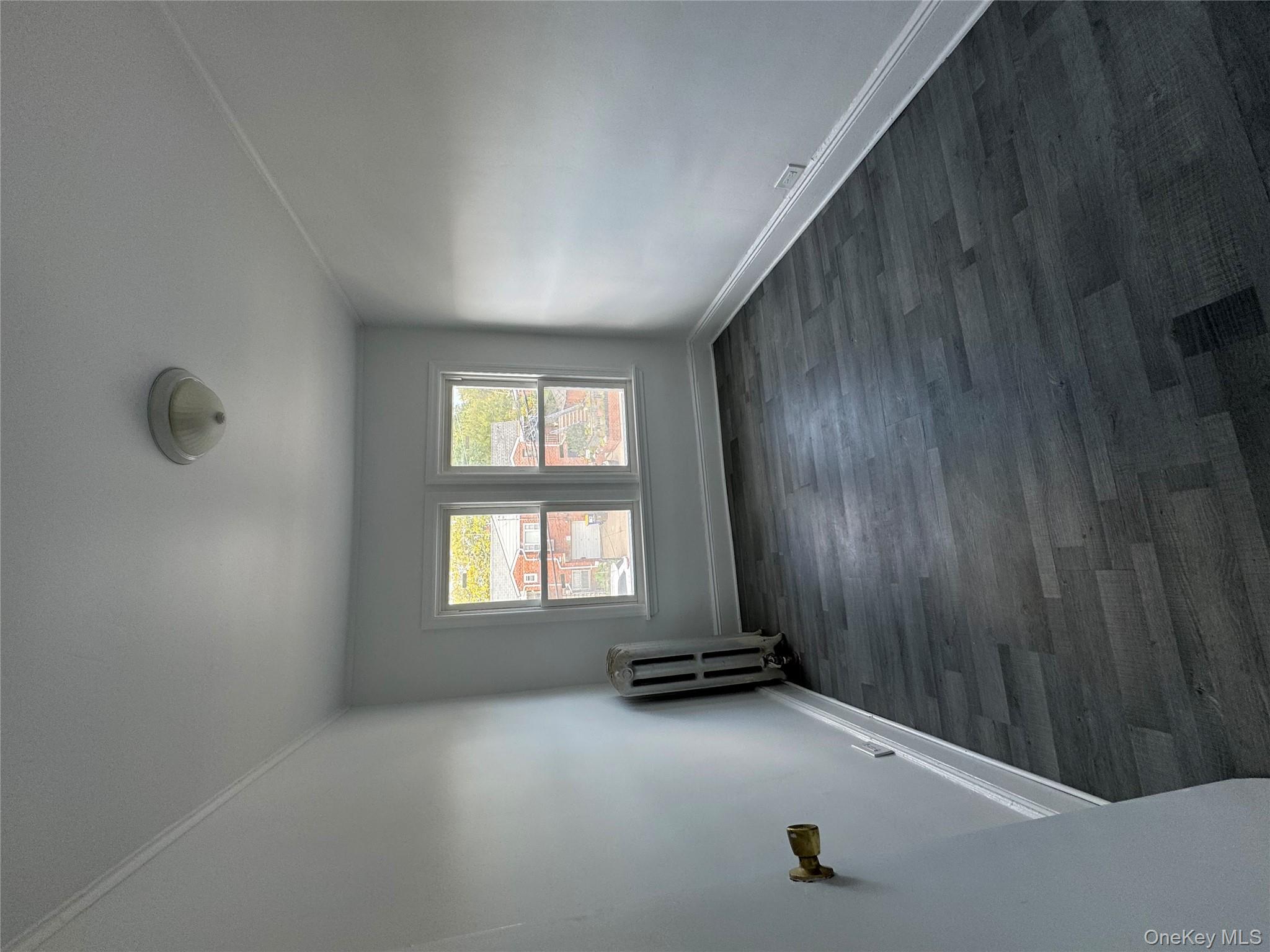 54-13 152nd Street Queens, NY 11355 - Photo 7 of 19 an empty room with wooden floor and windows