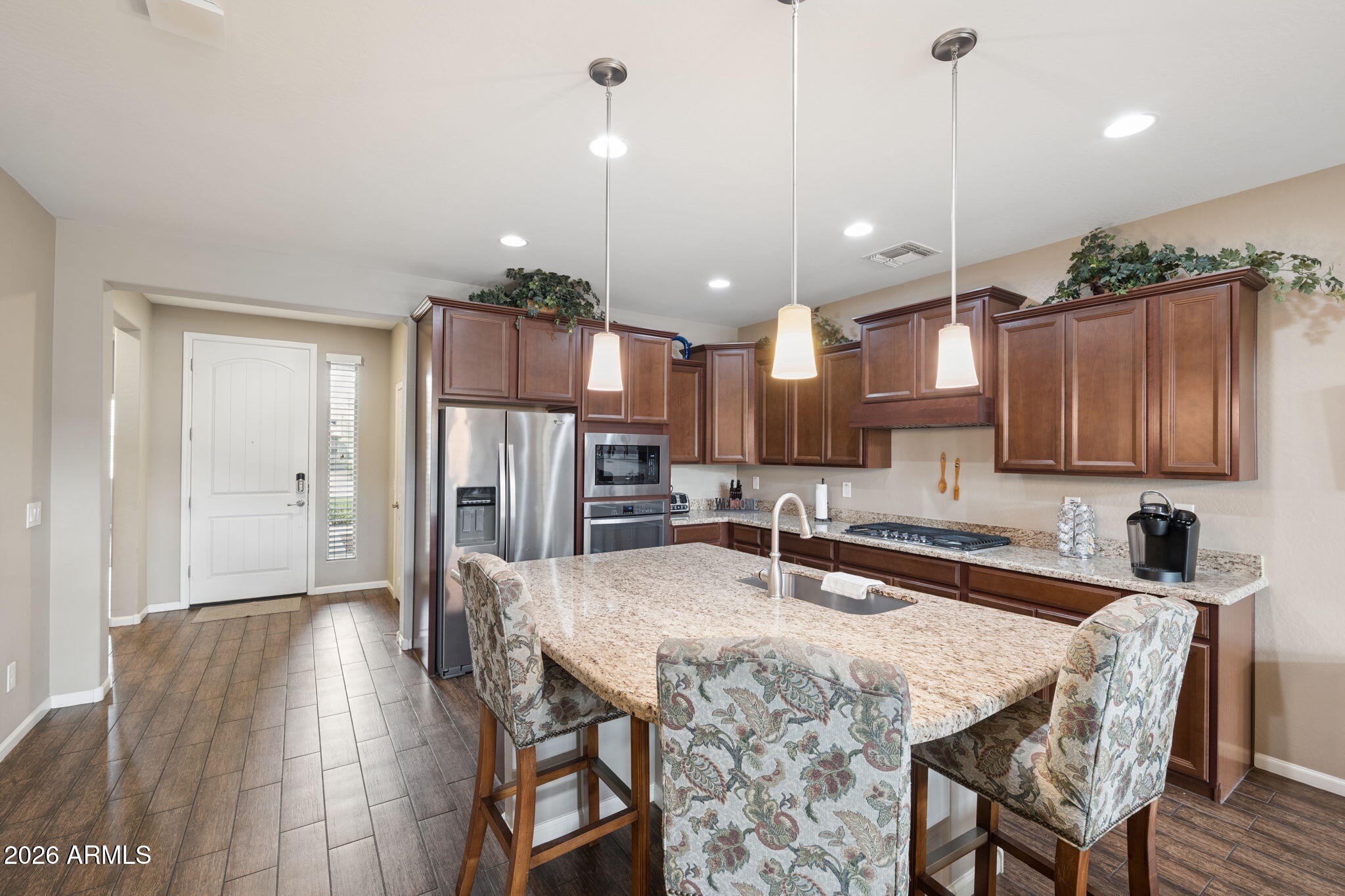 8993 West Ruth Avenue Peoria, AZ 85345 - Photo 3 of 24 a kitchen with granite countertop a table chairs refrigerator and microwave