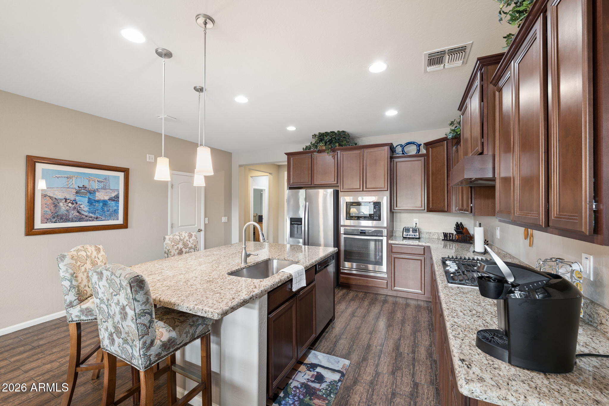 8993 West Ruth Avenue Peoria, AZ 85345 - Photo 4 of 24 a kitchen with stainless steel appliances granite countertop a refrigerator a sink dishwasher a stove and a dining table with wooden floor