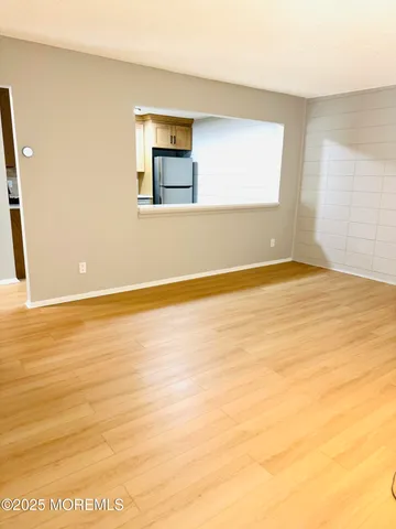 a view of an empty room with window and wooden floor
