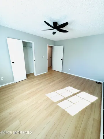 a view of a big room with wooden floor and windows