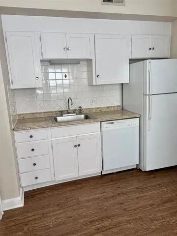 a kitchen with granite countertop white cabinets white stainless steel appliances and sink