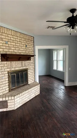 a view of an empty room with wooden floor and a fireplace