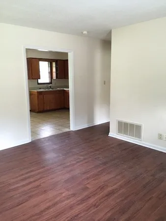 a view of a room with wooden floor and a kitchen