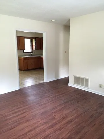 a view of a room with wooden floor and a kitchen