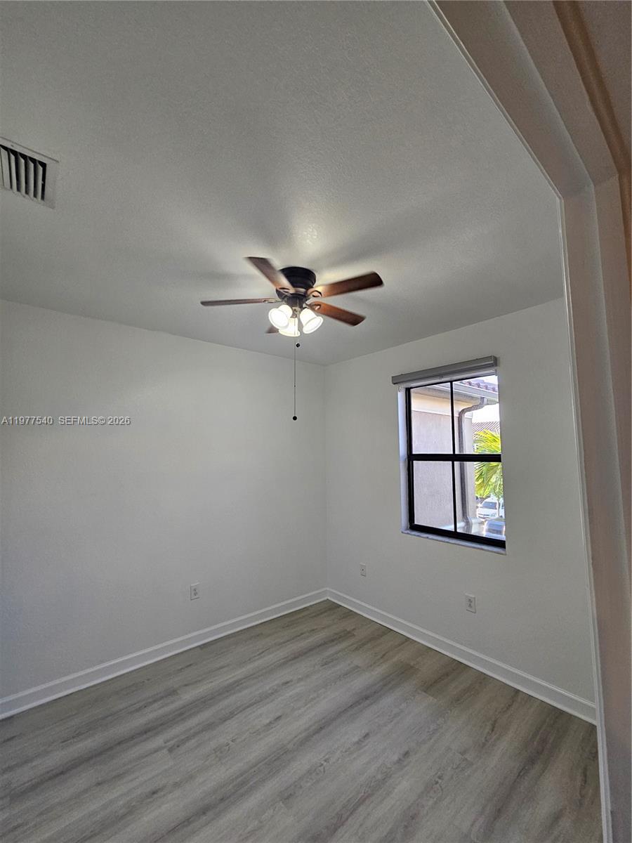 3370 West 90th Street, Unit A Hialeah, FL 33018 - Photo 28 of 40 an empty room with wooden floor ceiling fan and windows