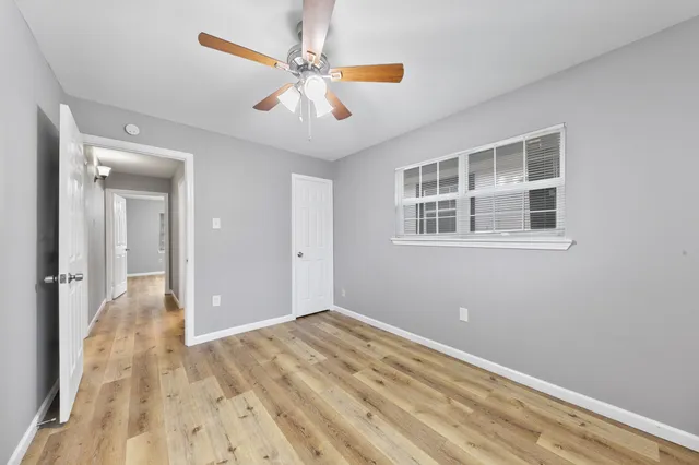 a view of a big room with wooden floor and chandelier fan