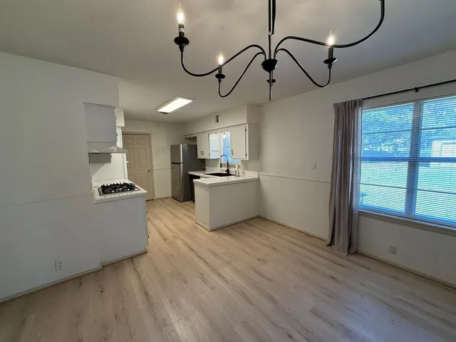 a kitchen with stainless steel appliances granite countertop a microwave a stove and white cabinets with wooden floor