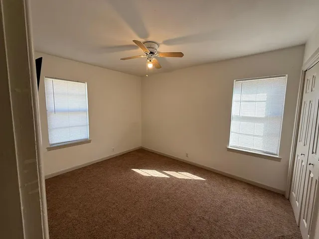 an empty room with windows and fan