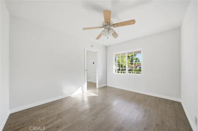 an empty room with wooden floor fan and windows