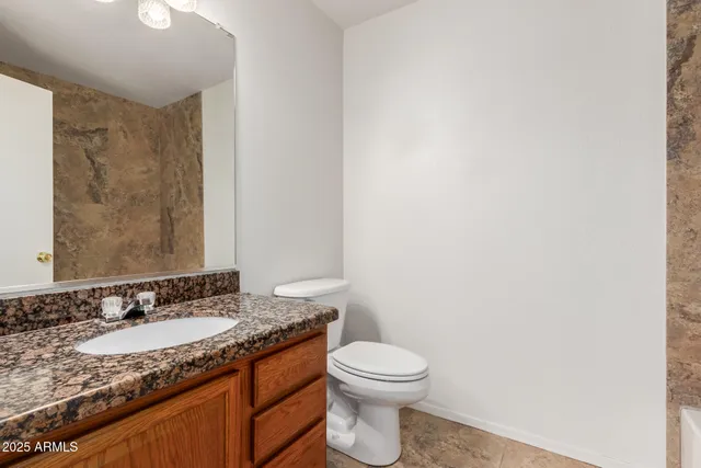 a bathroom with a granite countertop sink a toilet and a mirror