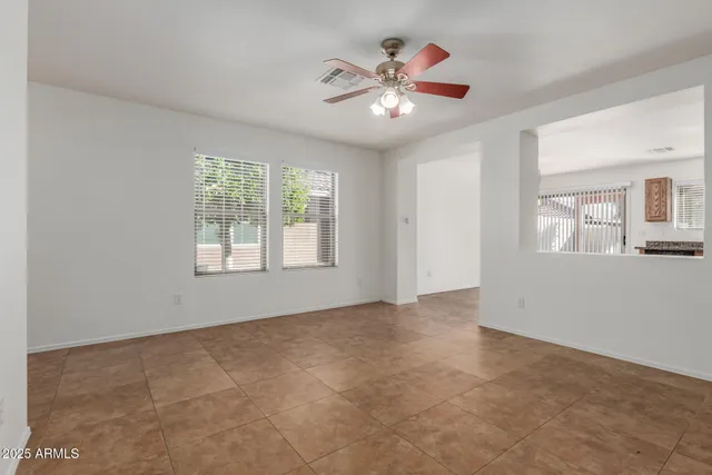 an empty room with windows and chandelier fan