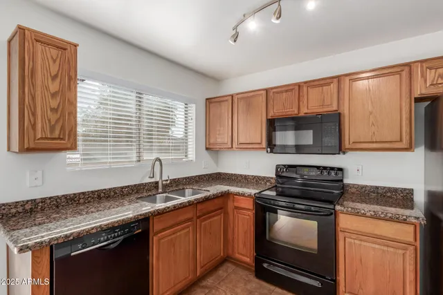 a kitchen with granite countertop a sink cabinets and stainless steel appliances
