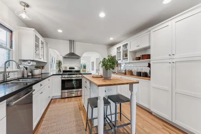 a kitchen with stainless steel appliances granite countertop wooden floor window and cabinets