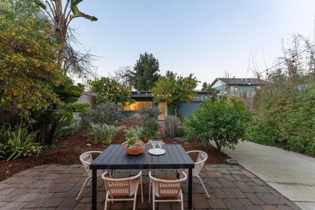 a view of a patio with table and chairs and potted plants with wooden floor and fence