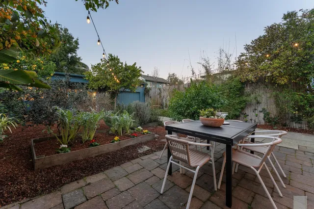 a patio with table and chairs and potted plants