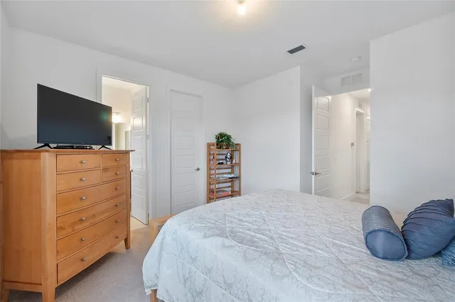 a bedroom with a bed and a flat tv screen on a dresser