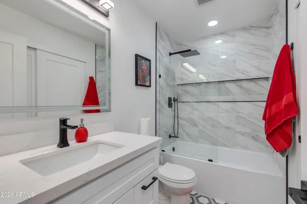 a bathroom with a tub sink vanity and toilet