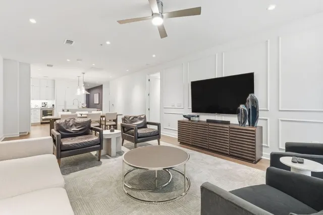 a kitchen with stainless steel appliances granite countertop a stove top oven a sink a dining table and chairs with wooden floor