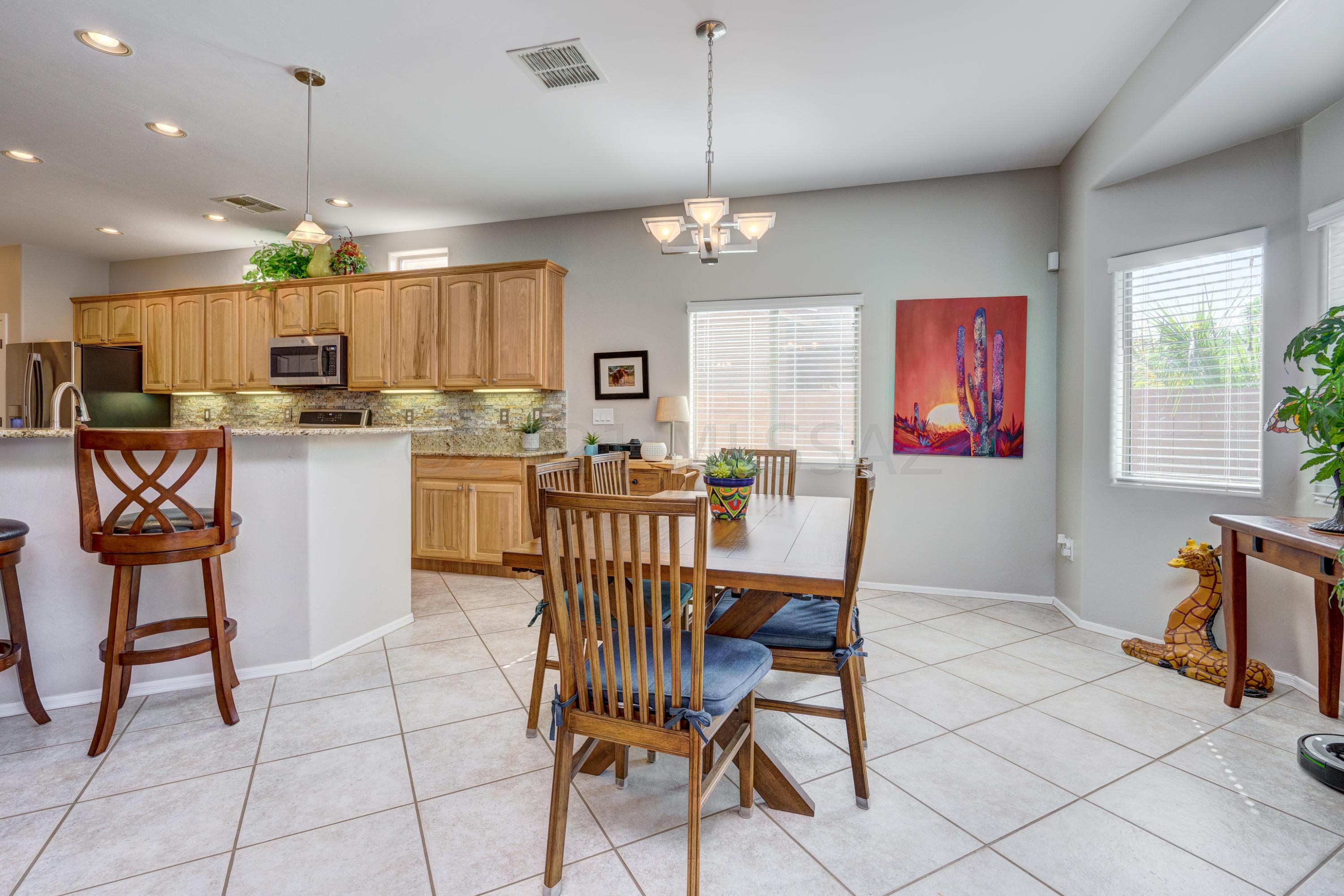 3639 East Northern Dancer Road Tucson, AZ 85739 - Photo 11 of 48 a kitchen with stainless steel appliances kitchen island granite countertop a dining table chairs and a refrigerator