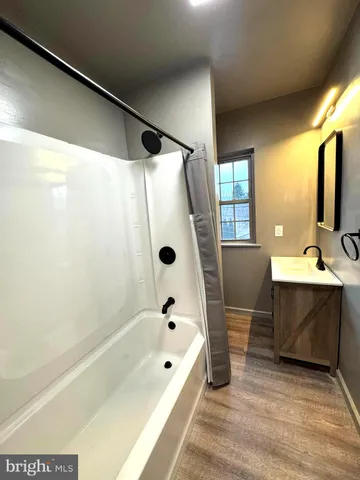 a bathroom with a tub sink and mirror