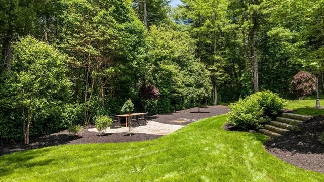 an aerial view of a house with a yard lake and trees all around
