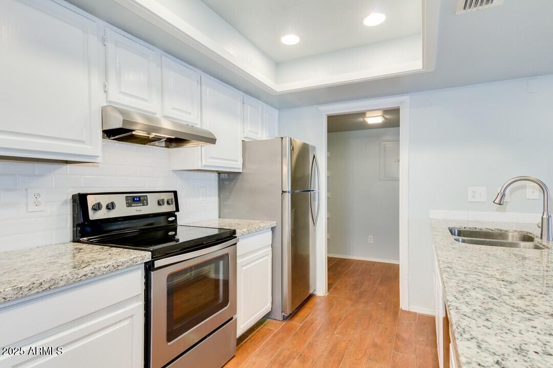 6900 East Gold Dust Avenue, Unit 149 Paradise Valley, AZ 85253 - Photo 15 of 34 a kitchen with granite countertop wooden cabinets and stainless steel appliances