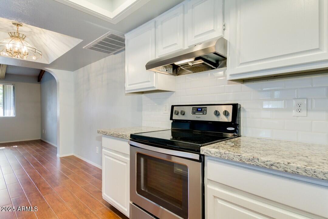 6900 East Gold Dust Avenue, Unit 149 Paradise Valley, AZ 85253 - Photo 19 of 34 a kitchen with granite countertop stainless steel appliances a stove cabinets and wooden floor
