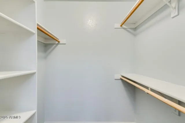 an empty room with a chandelier fan and windows