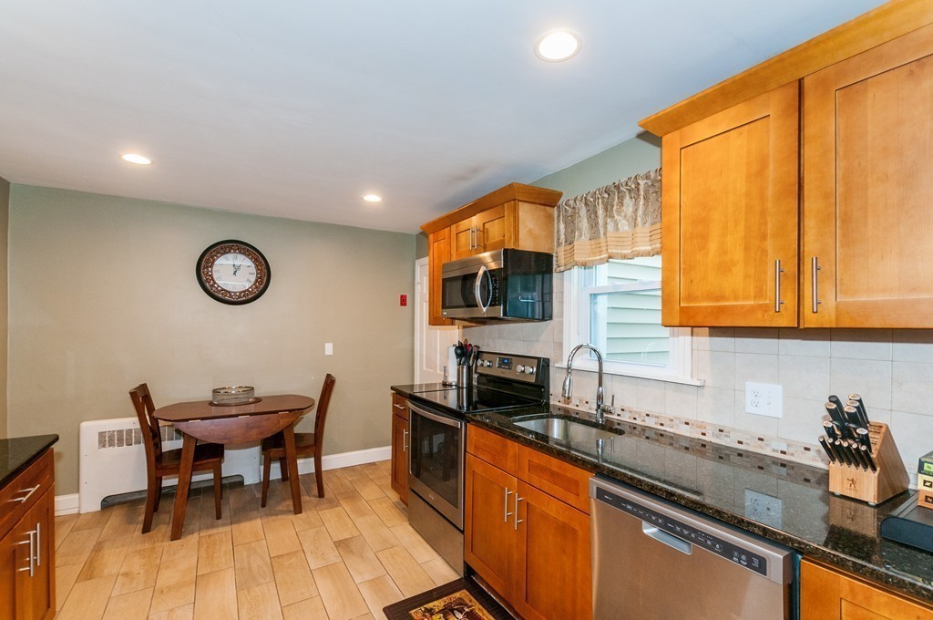 327 Edgell Road Framingham, MA 01701 - Photo 7 of 13 a kitchen with stainless steel appliances granite countertop a sink a stove cabinets dining table and chairs