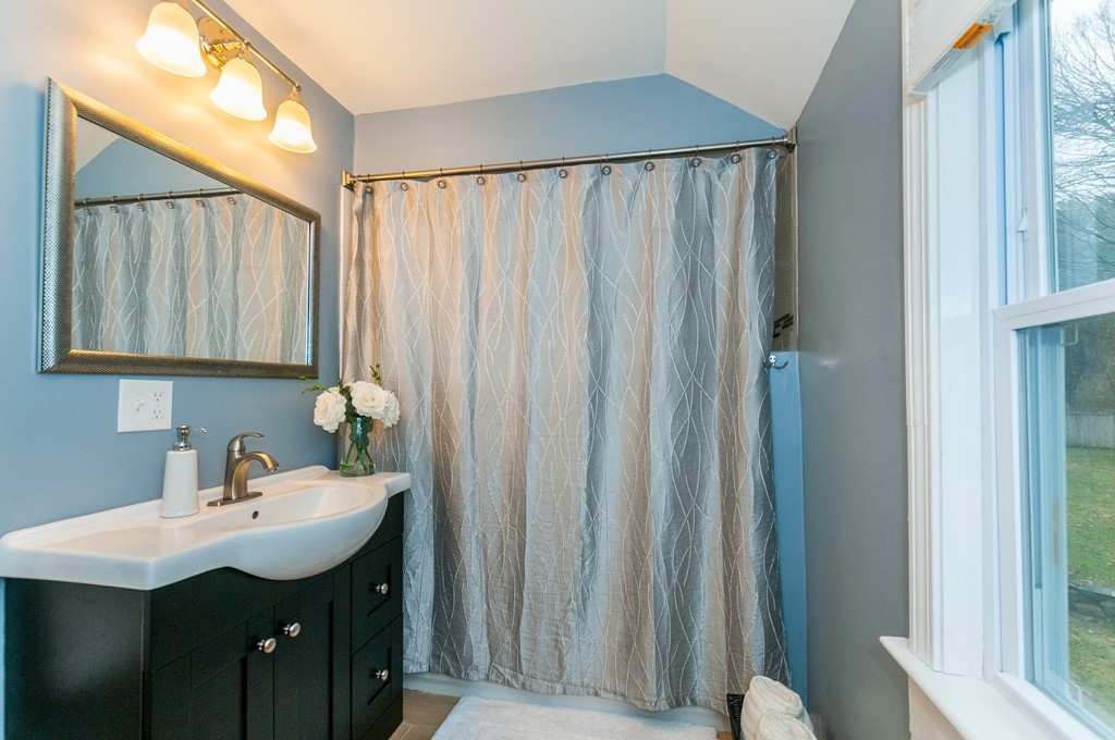 327 Edgell Road Framingham, MA 01701 - Photo 9 of 13 a bathroom with a sink a mirror and a shower curtain