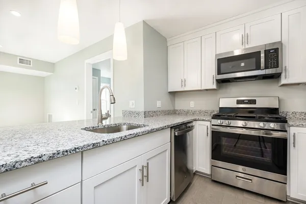 a kitchen with stainless steel appliances granite countertop white cabinets granite counter tops and a stove