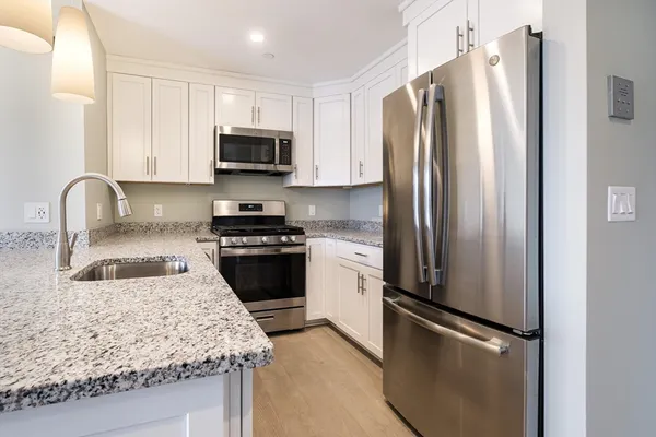 a kitchen with granite countertop a refrigerator stove and sink