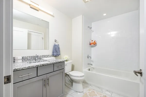 a bathroom with a granite countertop sink toilet and shower
