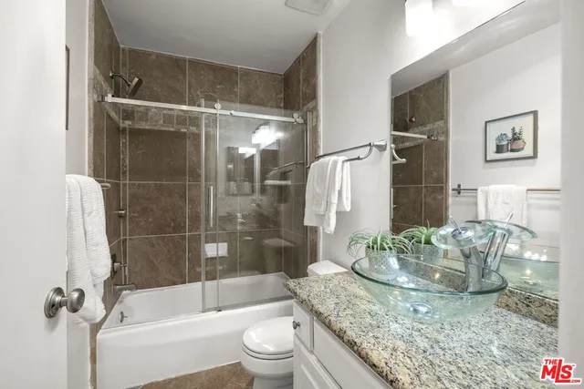 a bathroom with a granite countertop bathtub shower sink and toilet