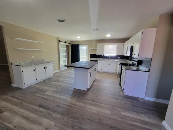 a kitchen with granite countertop a stove top oven and cabinets