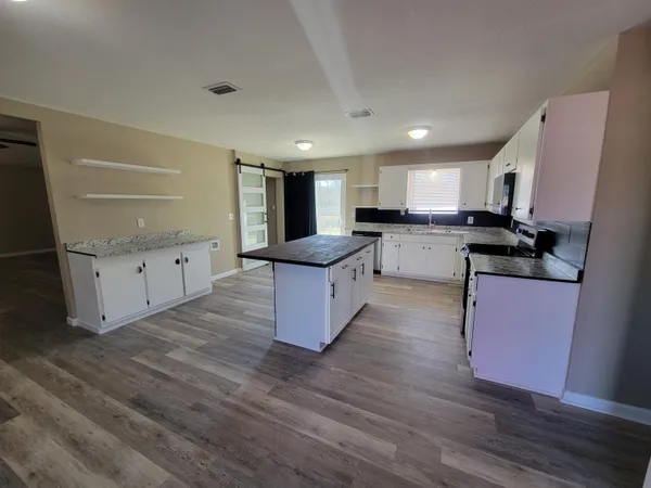 a kitchen with granite countertop a stove top oven and cabinets